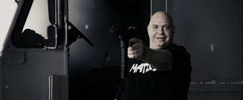 Movie still from “The Spirit” (2008), directed by Frank Miller – A bald man holding a gun in a room; Close Up shot, Low angle