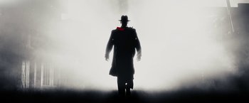 Movie still from “The Spirit” (2008), directed by Frank Miller – A man in a long coat and a red hat is in the fog; Wide shot, Low angle