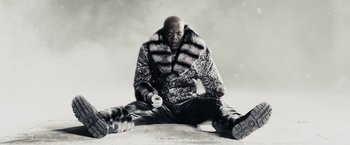 Movie still from “The Spirit” (2008), directed by Frank Miller – A man sitting on the ground holding a game controller; Medium shot, Low angle