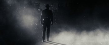 Movie still from “The Spirit” (2008), directed by Frank Miller – A man wearing a hat and a suit walking in the fog; Wide shot, Low angle