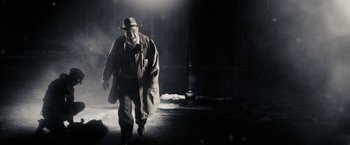 Movie still from “The Spirit” (2008), directed by Frank Miller – A man in a hat and coat walking in the dark; Medium shot, Low angle