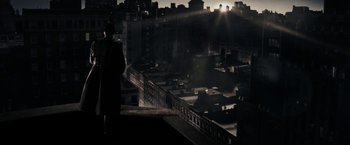 Movie still from “The Spirit” (2008), directed by Frank Miller – A man standing on a balcony looking over a city at night; Extreme Wide shot, Low angle