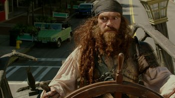 Movie still from “The SpongeBob Movie: Sponge Out of Water” (2015), directed by Mike Mitchell – A man dressed as a pirate holding the steering wheel of a boat; Close Up shot, Over the shoulder angle