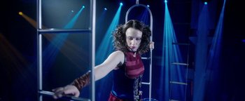 Movie still from “The Spy Who Dumped Me” (2018), directed by Susanna Fogel – A woman in a red and blue dress is holding a pole; Medium shot, Low angle