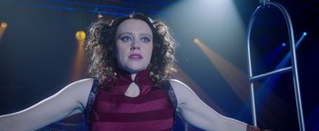 Movie still from “The Spy Who Dumped Me” (2018), directed by Susanna Fogel – A woman in a purple dress is posing for a picture; Close Up shot, Low angle