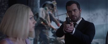 Movie still from “The Spy Who Dumped Me” (2018), directed by Susanna Fogel – A man holding a gun while standing next to a woman; Close Up shot, Over the shoulder angle