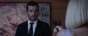 Movie still from “The Spy Who Dumped Me” (2018), directed by Susanna Fogel – A man wearing a suit and tie holding a gun; Close Up shot, Over the shoulder angle