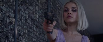 Movie still from “The Spy Who Dumped Me” (2018), directed by Susanna Fogel – A woman in a purple dress holding a gun in her hand; Close Up shot, Over the shoulder angle