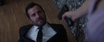 Movie still from “The Spy Who Dumped Me” (2018), directed by Susanna Fogel – A man wearing a suit and tie holding a gun; Close Up shot, Over the shoulder angle