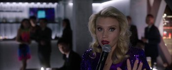 Movie still from “The Spy Who Dumped Me” (2018), directed by Susanna Fogel – A woman with a microphone in her hand; Close Up shot, Over the shoulder angle