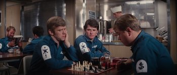 Movie still from “The Spy Who Loved Me” (1977), directed by Lewis Gilbert – A group of young men playing a game of chess in a restaurant; Medium shot, Over the shoulder angle