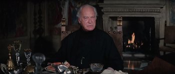 Movie still from “The Spy Who Loved Me” (1977), directed by Lewis Gilbert – An older man sitting at a dinner table; Close Up shot, Low angle