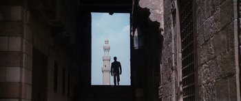 Movie still from “The Spy Who Loved Me” (1977), directed by Lewis Gilbert – A man standing in front of a window with a view of a building; Wide shot, Low angle