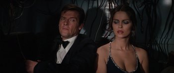 Movie still from “The Spy Who Loved Me” (1977), directed by Lewis Gilbert – A man and a woman sitting next to each other in formal wear; Medium shot, Low angle