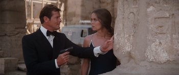 Movie still from “The Spy Who Loved Me” (1977), directed by Lewis Gilbert – A man and a woman in a black dress holding a gun; Medium shot, Over the shoulder angle