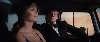 Movie still from “The Spy Who Loved Me” (1977), directed by Lewis Gilbert – A man and a woman sitting in the back of a car; Medium shot, Low angle