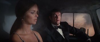 Movie still from “The Spy Who Loved Me” (1977), directed by Lewis Gilbert – A man and a woman sitting in the back of a car; Medium shot, Low angle