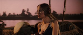 Movie still from “The Spy Who Loved Me” (1977), directed by Lewis Gilbert – A beautiful young lady sitting on a chair in front of a body of water at dusk; Medium shot, Over the shoulder angle