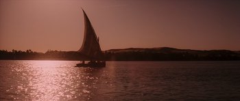 Movie still from “The Spy Who Loved Me” (1977), directed by Lewis Gilbert – A sailboat sailing on a body of water at sunset; Extreme Wide shot, Low angle