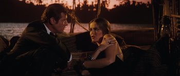 Movie still from “The Spy Who Loved Me” (1977), directed by Lewis Gilbert – A man and a woman sitting next to each other on a couch; Medium shot, Over the shoulder angle