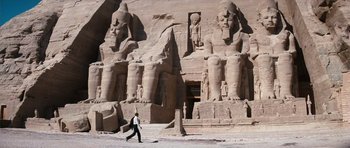Movie still from “The Spy Who Loved Me” (1977), directed by Lewis Gilbert – A man walking in front of a large building with statues; Extreme Wide shot, Low angle