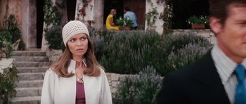 Movie still from “The Spy Who Loved Me” (1977), directed by Lewis Gilbert – A woman standing in front of bushes and a building; Medium shot, Over the shoulder angle