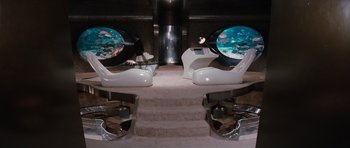 Movie still from “The Spy Who Loved Me” (1977), directed by Lewis Gilbert – A couple of chairs with a fish tank in the middle of them; Wide shot, High angle