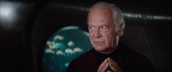 Movie still from “The Spy Who Loved Me” (1977), directed by Lewis Gilbert – An older man with white hair and a black shirt; Close Up shot, Low angle