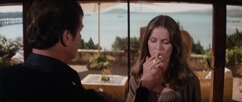 Movie still from “The Spy Who Loved Me” (1977), directed by Lewis Gilbert – A man and a woman are sitting at a table and one of them is smoking a cigarette; Medium shot, Over the shoulder angle
