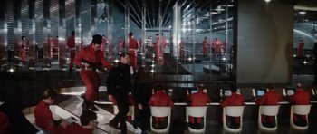 Movie still from “The Spy Who Loved Me” (1977), directed by Lewis Gilbert – A group of people in red suits in a room with glass walls; Wide shot, High angle