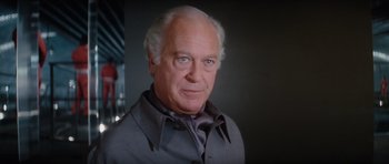 Movie still from “The Spy Who Loved Me” (1977), directed by Lewis Gilbert – An older man wearing a gray shirt and a gray tie; Close Up shot, Low angle