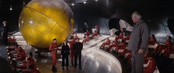 Movie still from “The Spy Who Loved Me” (1977), directed by Lewis Gilbert – A group of people dressed in red are standing in front of a globe; Extreme Wide shot, High angle