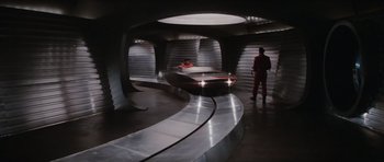 Movie still from “The Spy Who Loved Me” (1977), directed by Lewis Gilbert – Two people standing next to a curved metal walkway; Wide shot, High angle