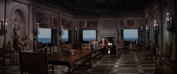 Movie still from “The Spy Who Loved Me” (1977), directed by Lewis Gilbert – A man sitting at a table in front of a fireplace; Extreme Wide shot, High angle