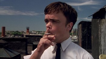 Movie still from “The Station Agent” (2003), directed by Tom McCarthy – A man in a white dress shirt and black tie smoking a cigarette; Close Up shot, Low angle