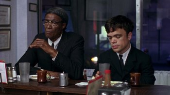 Movie still from “The Station Agent” (2003), directed by Tom McCarthy – Two men sitting at a table in a restaurant; Medium shot, Over the shoulder angle