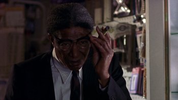 Movie still from “The Station Agent” (2003), directed by Tom McCarthy – A man in a suit and tie holding a cigar; Close Up shot, Low angle