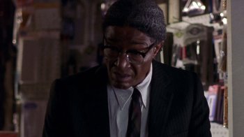 Movie still from “The Station Agent” (2003), directed by Tom McCarthy – A man in a suit and tie wearing glasses; Close Up shot, Over the shoulder angle