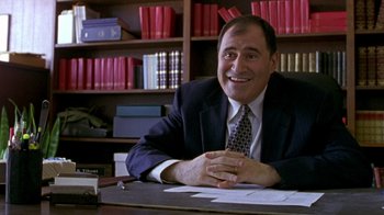 Movie still from “The Station Agent” (2003), directed by Tom McCarthy – A man sitting at a desk in front of a book shelf; Medium shot, High angle