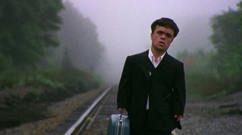 Movie still from “The Station Agent” (2003), directed by Tom McCarthy – A man in a suit holding a briefcase on the side of a train track; Medium shot, Low angle