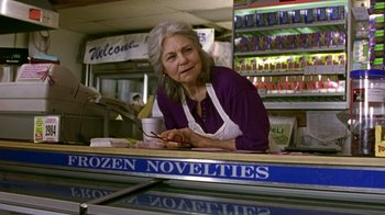 Movie still from “The Station Agent” (2003), directed by Tom McCarthy – An older woman sitting at a counter in a store; Medium shot, Low angle