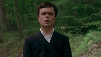 Movie still from “The Station Agent” (2003), directed by Tom McCarthy – A man in a black suit standing in the woods; Close Up shot, High angle