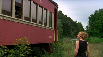 Movie still from “The Station Agent” (2003), directed by Tom McCarthy – A woman standing in front of a red train car; Wide shot, Low angle