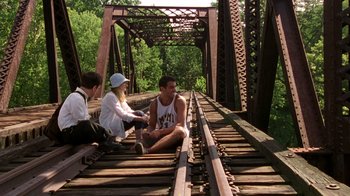 Movie still from “The Station Agent” (2003), directed by Tom McCarthy – A group of people sitting on top of a train track; Wide shot, Low angle
