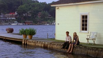 Movie still from “The Station Agent” (2003), directed by Tom McCarthy – A man and a woman sitting on the edge of a dock; Wide shot, High angle