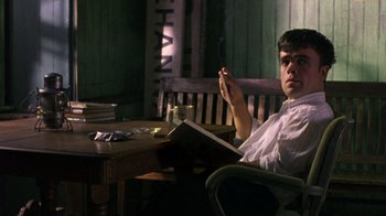 Movie still from “The Station Agent” (2003), directed by Tom McCarthy – A man sitting at a table with a book in front of him; Medium shot, Low angle