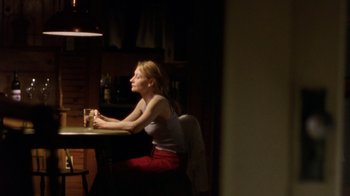 Movie still from “The Station Agent” (2003), directed by Tom McCarthy – A woman sitting at a table with a glass of water; Medium shot, Over the shoulder angle
