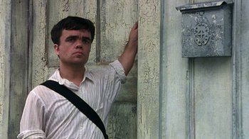 Movie still from “The Station Agent” (2003), directed by Tom McCarthy – A man in a striped shirt leaning against a wall; Close Up shot, Low angle