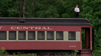 Movie still from “The Station Agent” (2003), directed by Tom McCarthy – A man standing on top of a red train car; Extreme Wide shot, Low angle