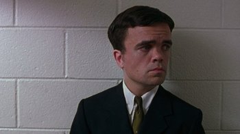Movie still from “The Station Agent” (2003), directed by Tom McCarthy – A man wearing a suit and tie standing in front of a wall; Close Up shot, Low angle